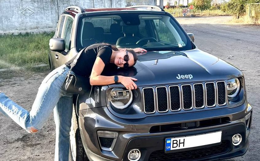 Счастливая девушка обнимает автомобиль марки Jeep, который она купила через компанию W8 Shipping